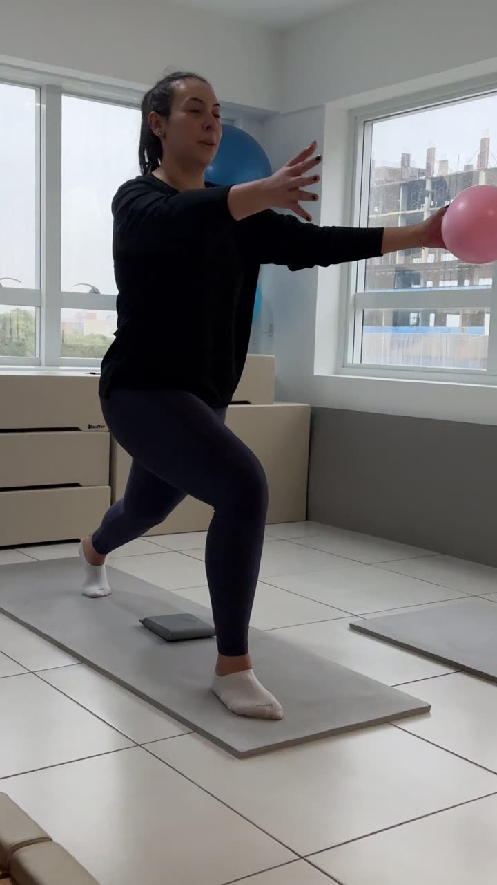 Aluna jovem da Soliê em apoio unipodal sobre tatame, braços abertos lateralmente formando um T, joelho contralateral elevado. Exercício clássico de propriocepção e equilíbrio dinâmico, recrutando estabilizadores do quadril, core profundo e musculatura intrínseca do pé.